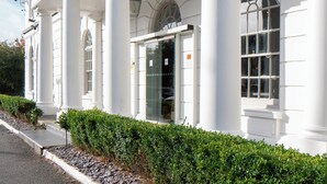 En vit byggnad med kolonner och en balkong, troligen ett hotell eller en offentlig byggnad.