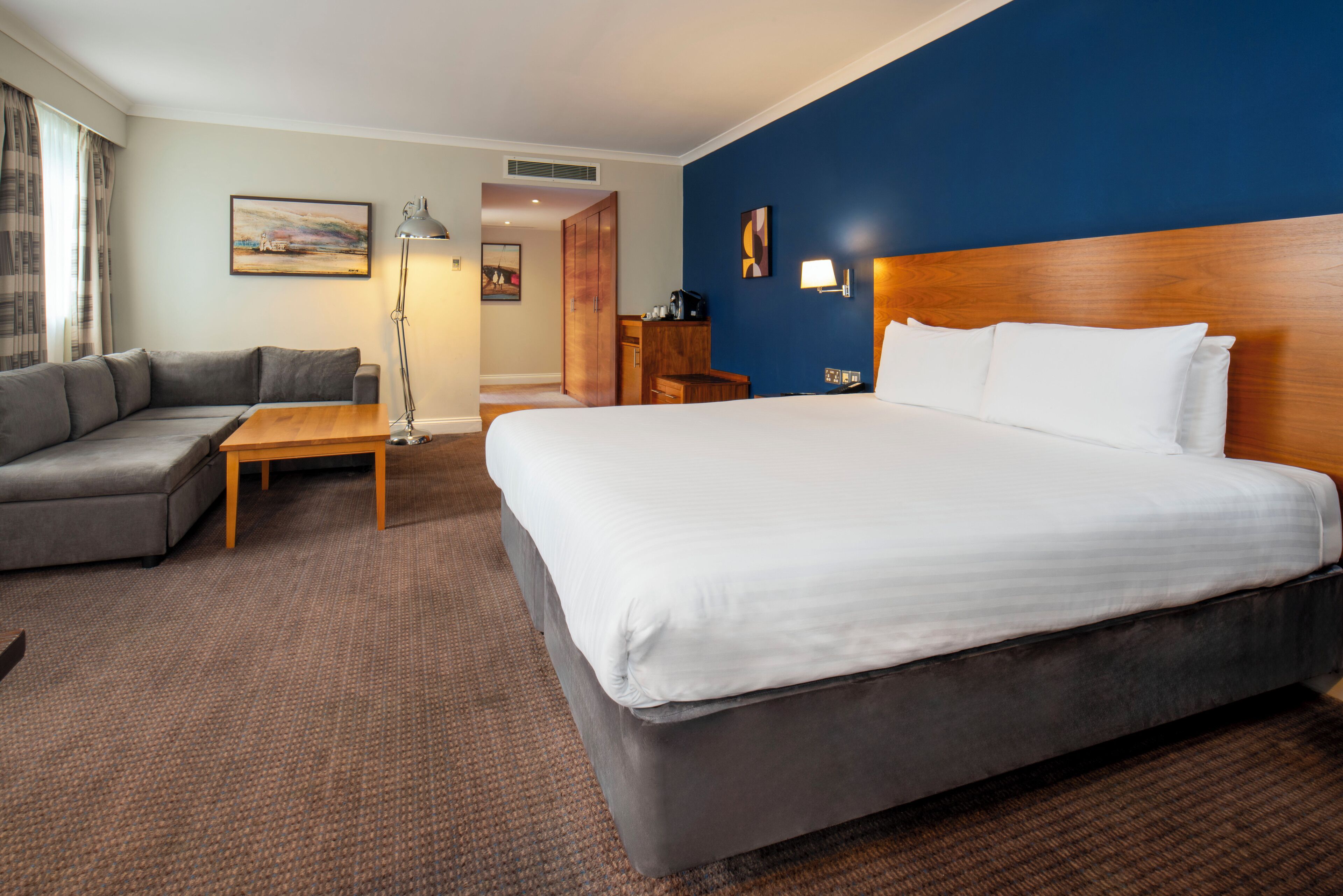 Ein Hotelzimmer mit einem großen Bett, einer Couch, einem Schreibtisch und einer Lampe.