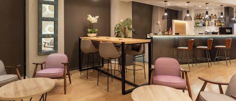 Een moderne barruimte met houten tafels en stoelen, een bargedeelte met flessen en een decoratieve spiegel aan de muur.