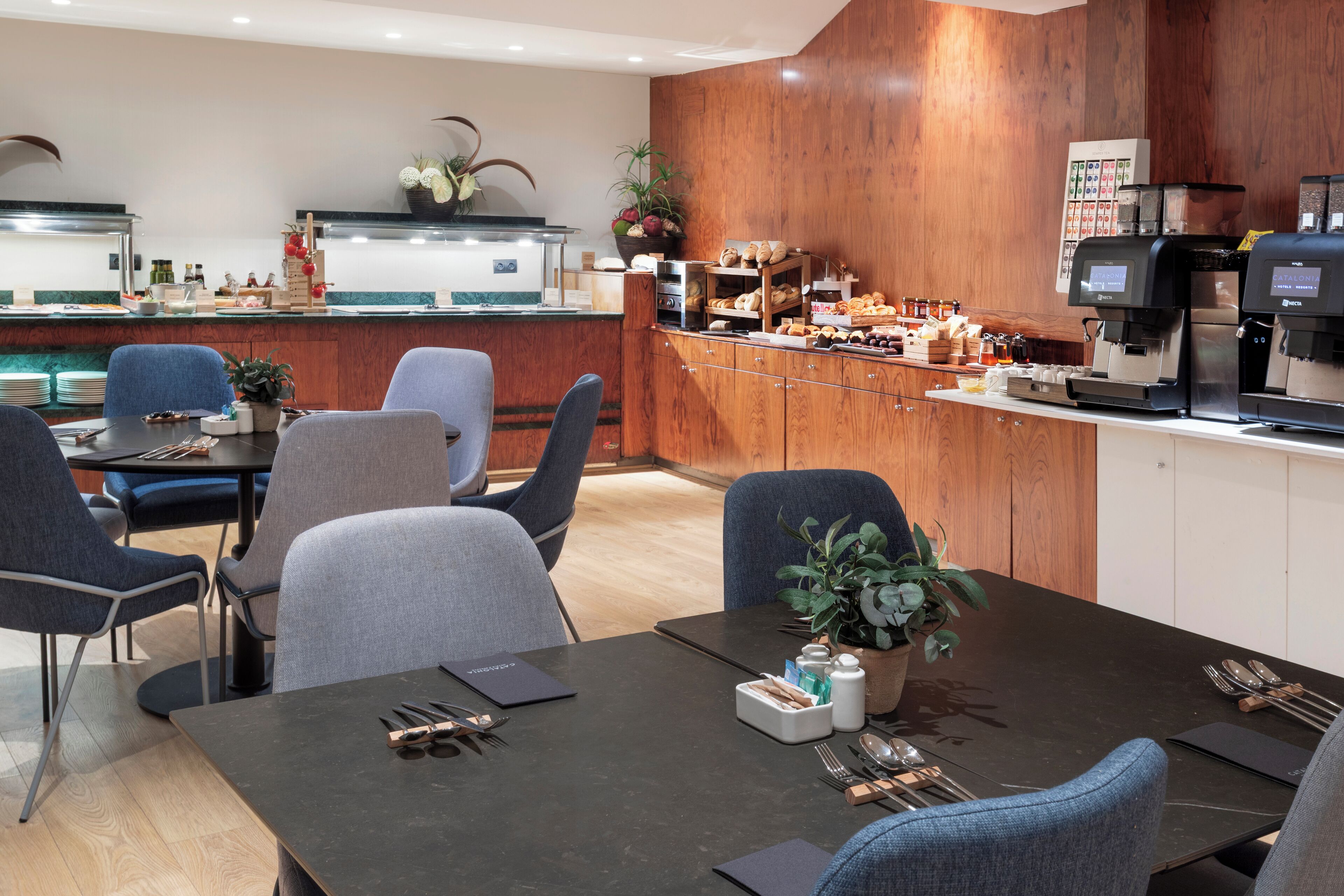Comedor de hotel con bufé, disposición de mesas y máquinas de café.
