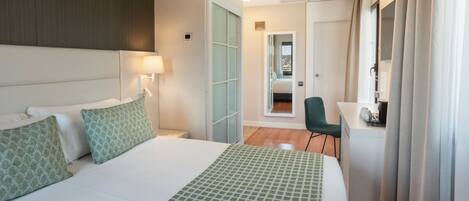 A hotel room with a large bed, a desk, and a chair.