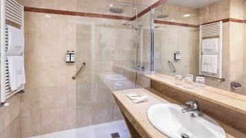 A modern bathroom with a glass-enclosed shower, a large sink, and a vanity with a mirror.