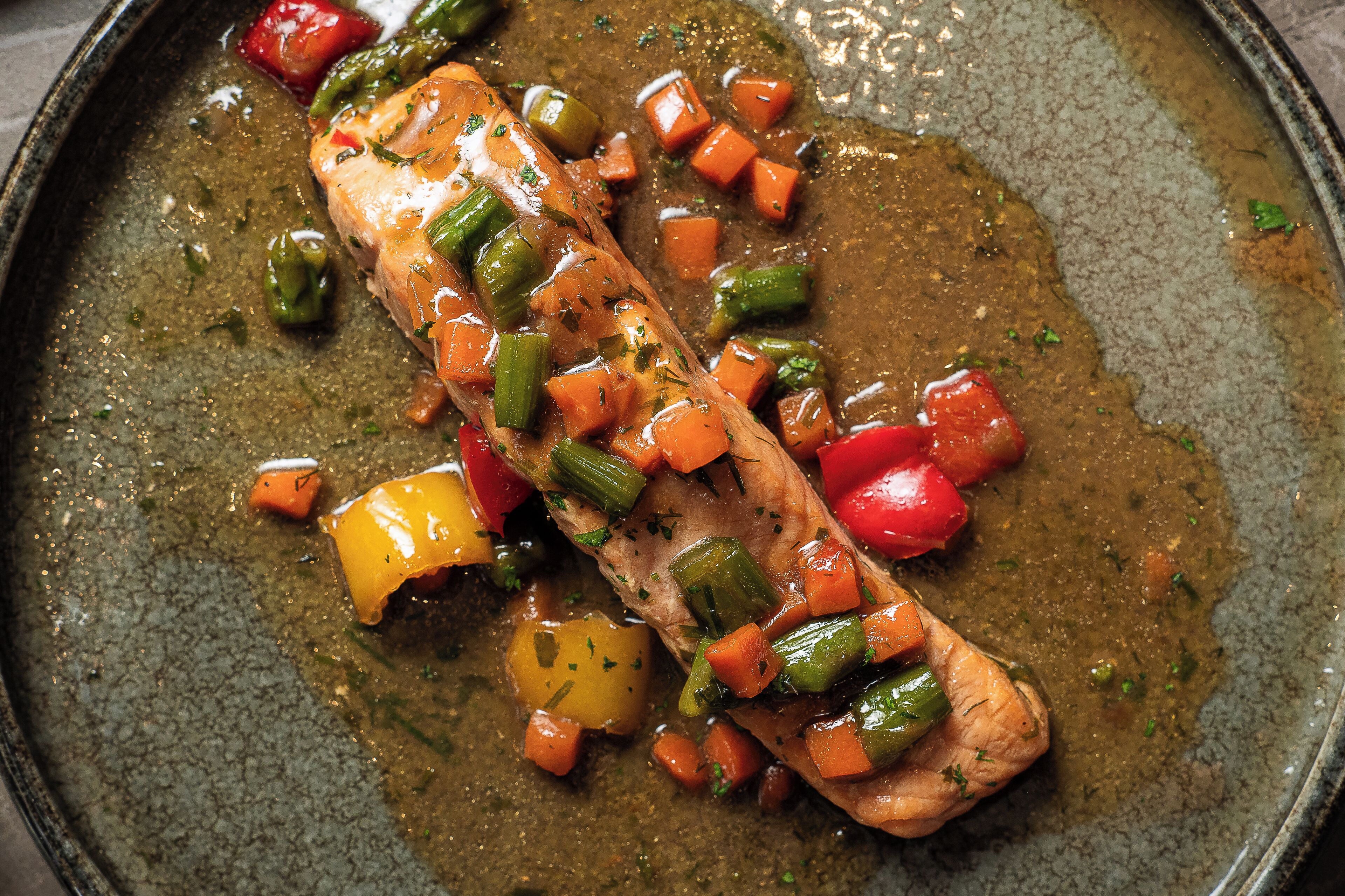 A salmon fillet with vegetables in a pan.