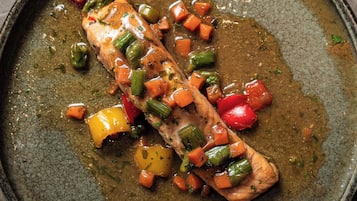 A salmon fillet with vegetables in a pan.