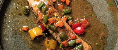 A salmon fillet with vegetables in a pan.