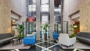 Um lobby moderno com padrão geométrico no chão, áreas de estar e amplas janelas de vidro.