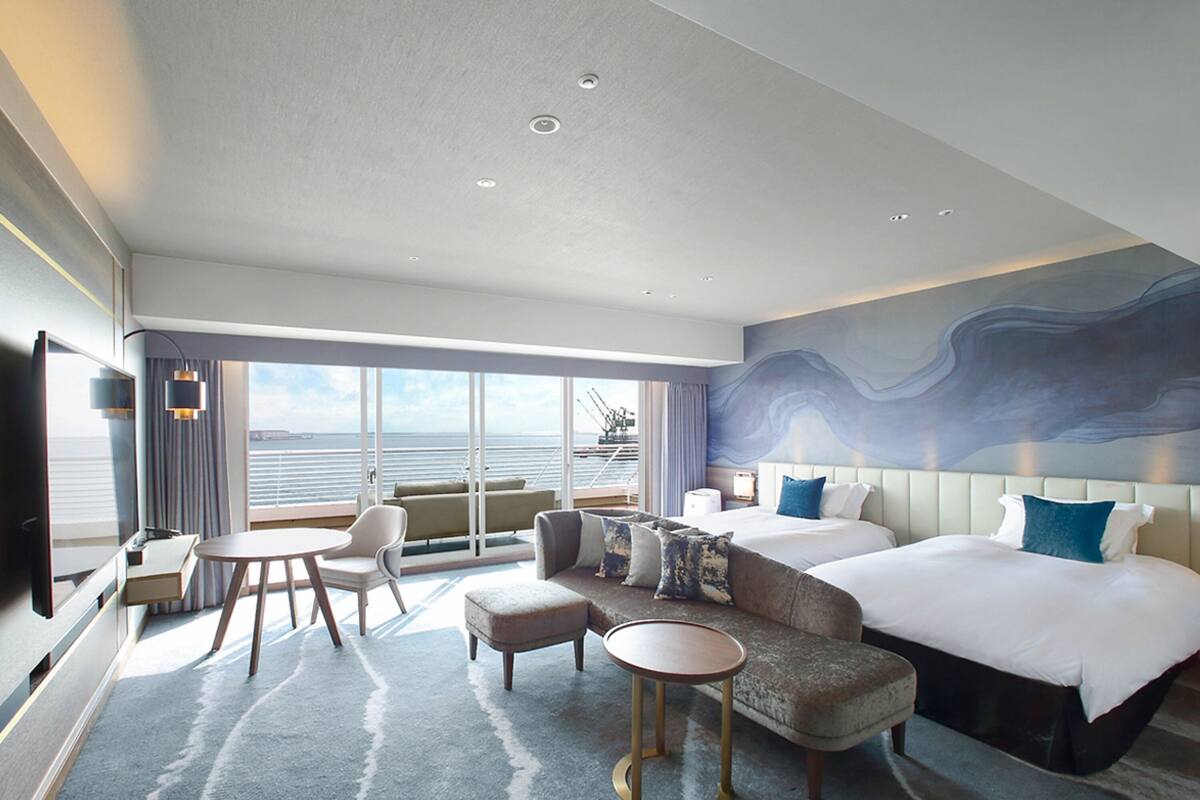 Una habitación de hotel moderna con una cama grande, un sofá, una mesita y un televisor.