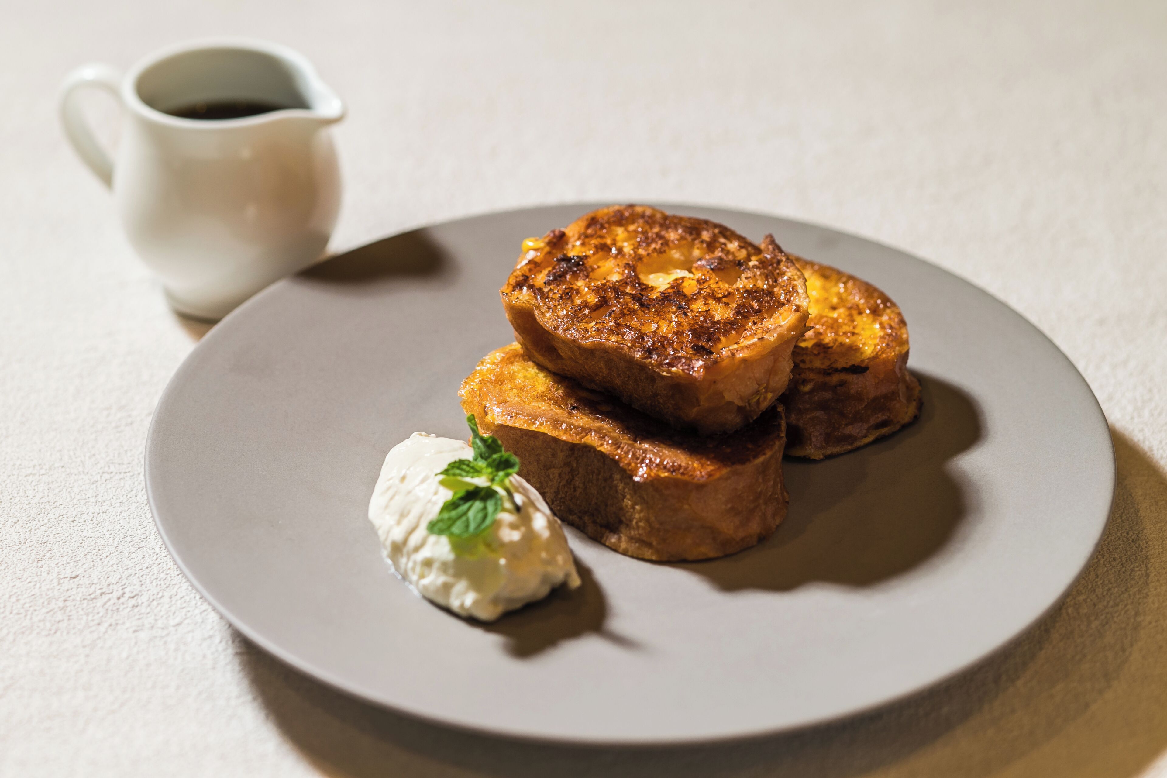 A plate with two pieces of toast and a dollop of cream on a round plate.