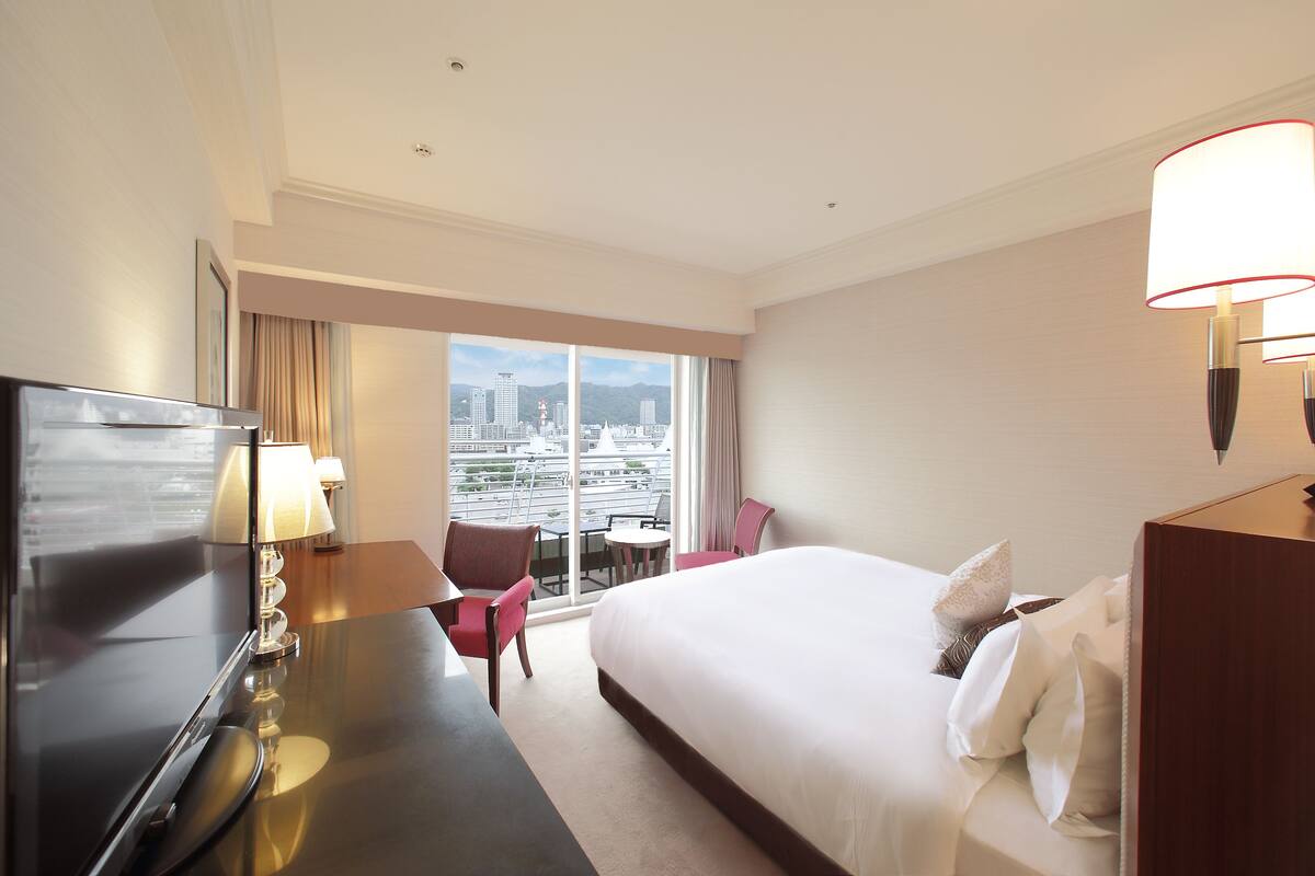 Habitación de hotel con cama, escritorio, televisión y una silla.