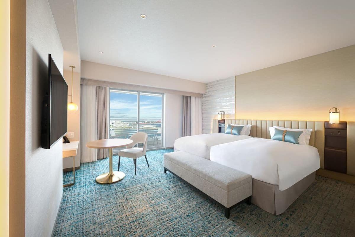 Una habitación de hotel con una cama grande, un escritorio, una silla y un televisor.