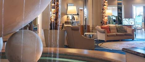 A lobby with a water feature, seating area, and a television.