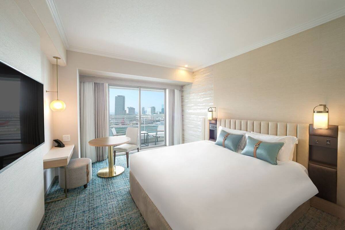 Una habitación de hotel con una cama grande, un escritorio con silla, una mesita y un televisor.