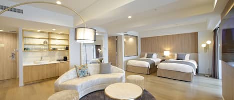 Una habitación de hotel moderna con un sofá curvo, una mesa redonda, una cama con dos almohadas, una mesita de noche con lámpara y un espejo grande.