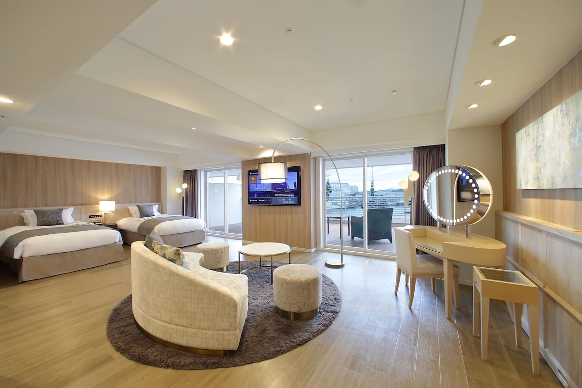 Una habitación de hotel moderna con una cama grande, un sofá, un escritorio con espejo y un televisor.