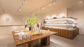 Un moderno y minimalista vestíbulo de hotel con un mostrador de recepción de madera, una gran planta en maceta y una paleta de colores limpia en blanco.