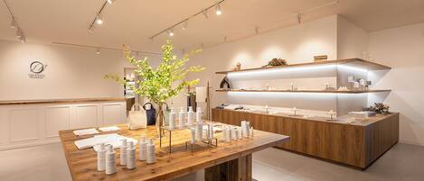Un hall d’hôtel moderne et minimaliste, avec un comptoir d’accueil en bois, une grande plante en pot et une décoration aux couleurs sobres et blanches.
