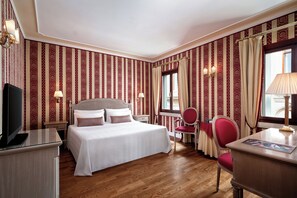 A hotel room with a bed, a desk, a chair, a television, and a window with curtains. - Sina Palazzo Sant'Angelo (Venice)