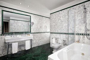 Un baño con un espejo grande, dos lavamanos, un inodoro, una bañera y una ducha.