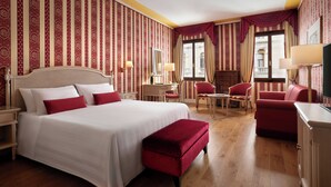 Une chambre d’hôtel avec un grand lit, un bureau, deux chaises, une petite table et un téléviseur.