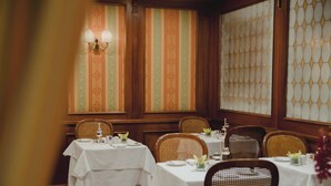 Un restaurant avec de nombreuses tables, des chaises en osier et un papier peint à motifs.