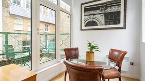 Ein Zimmer mit Glastisch, zwei Ledersesseln, einem Blumentopf und einem gerahmten Bild an der Wand.