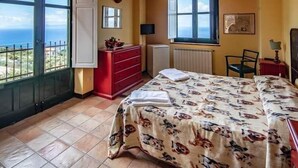 Un dormitorio con cama, cómoda, silla, ventana con vistas y radiador.