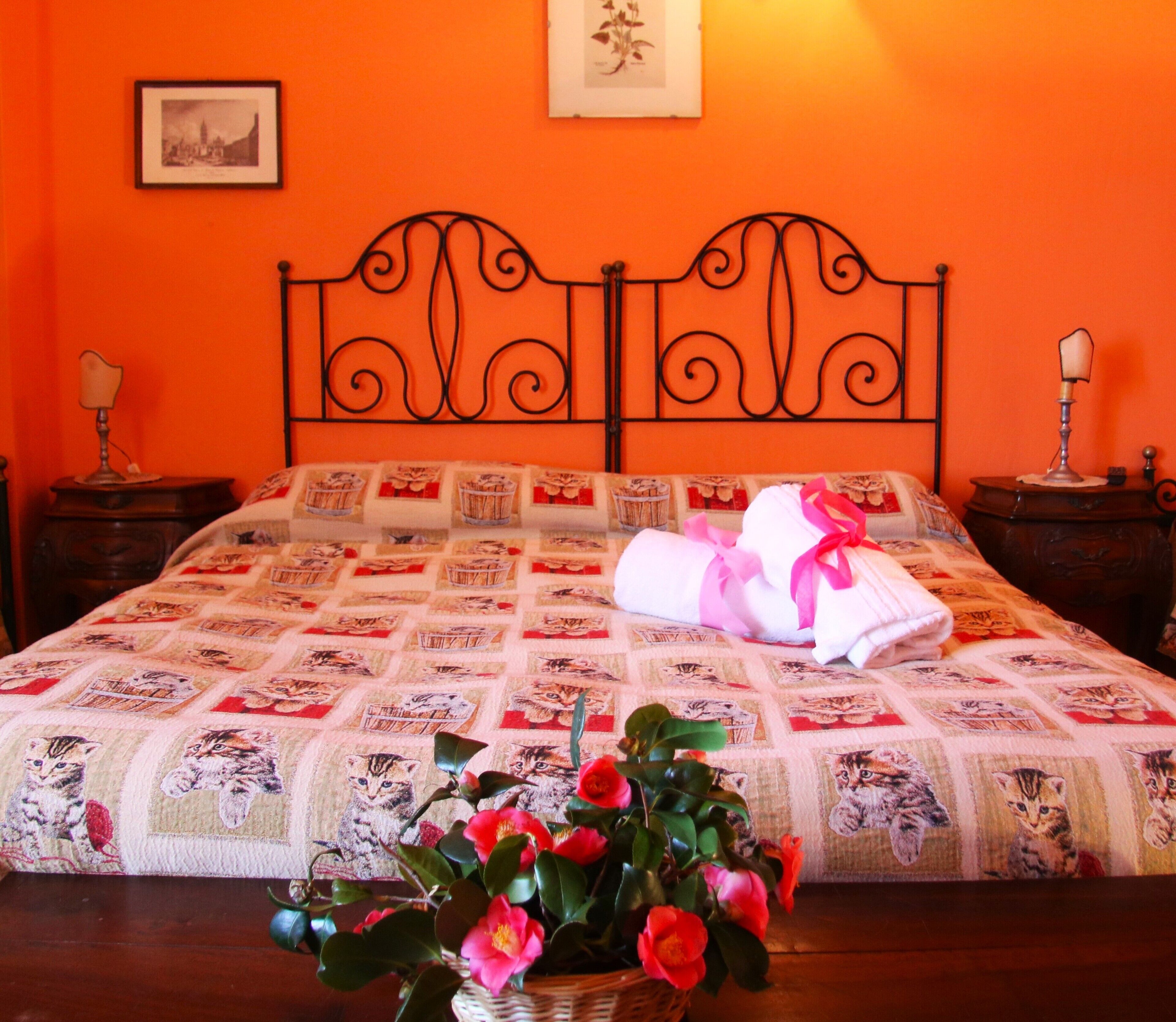 Una camera da letto con un letto, due comodini, un tavolino e un quadro appeso al muro, oltre a una pianta in vaso.