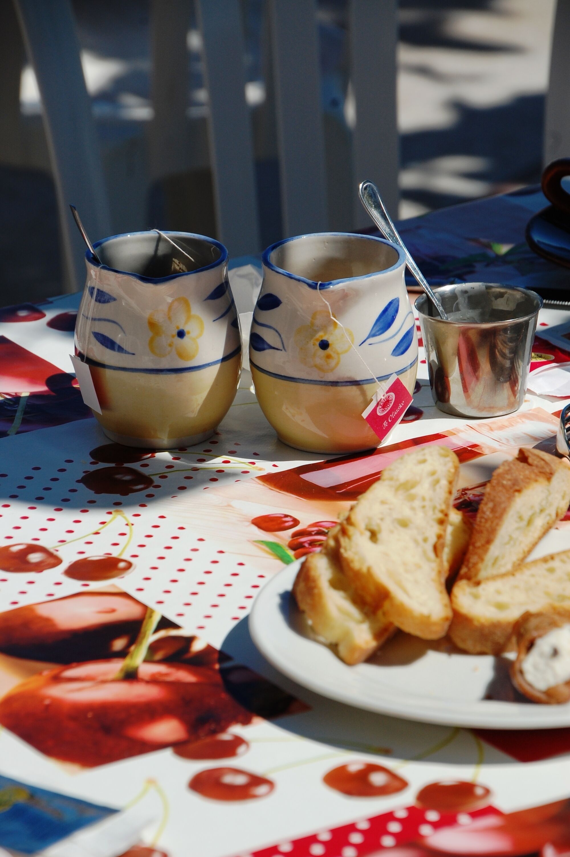 Een tafel met twee keramische bekers, een metalen beker en een bord met brood.