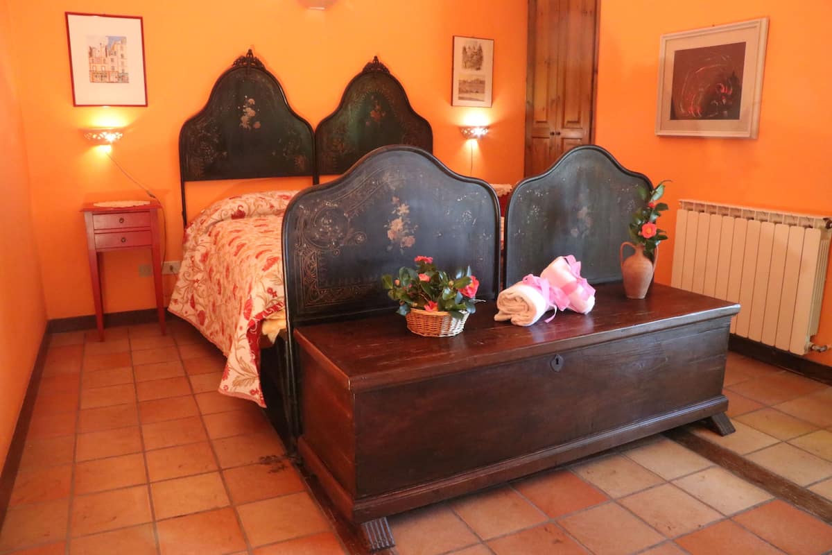 Ein Schlafzimmer mit einem hölzernen Bett, einem Nachttisch, einer Kommode und einer Heizung.