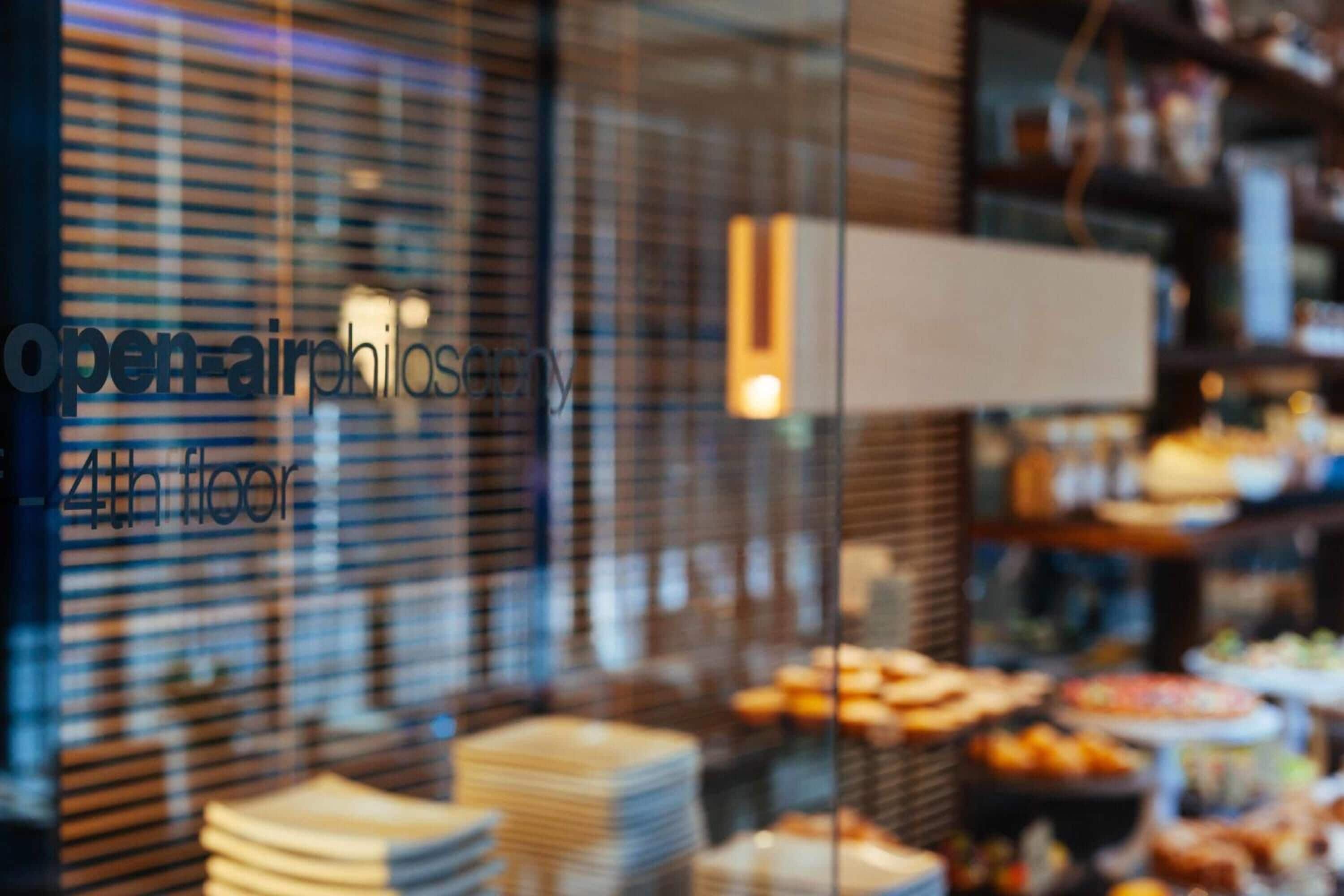 A blurred view of a buffet area with various food items and a glass partition with text.