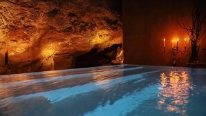 A spa area with a reflective pool, a candlelit candelabra, and a cave-like wall. - UNA Hotels One Siracusa Wellness & SPA (Syracuse)
