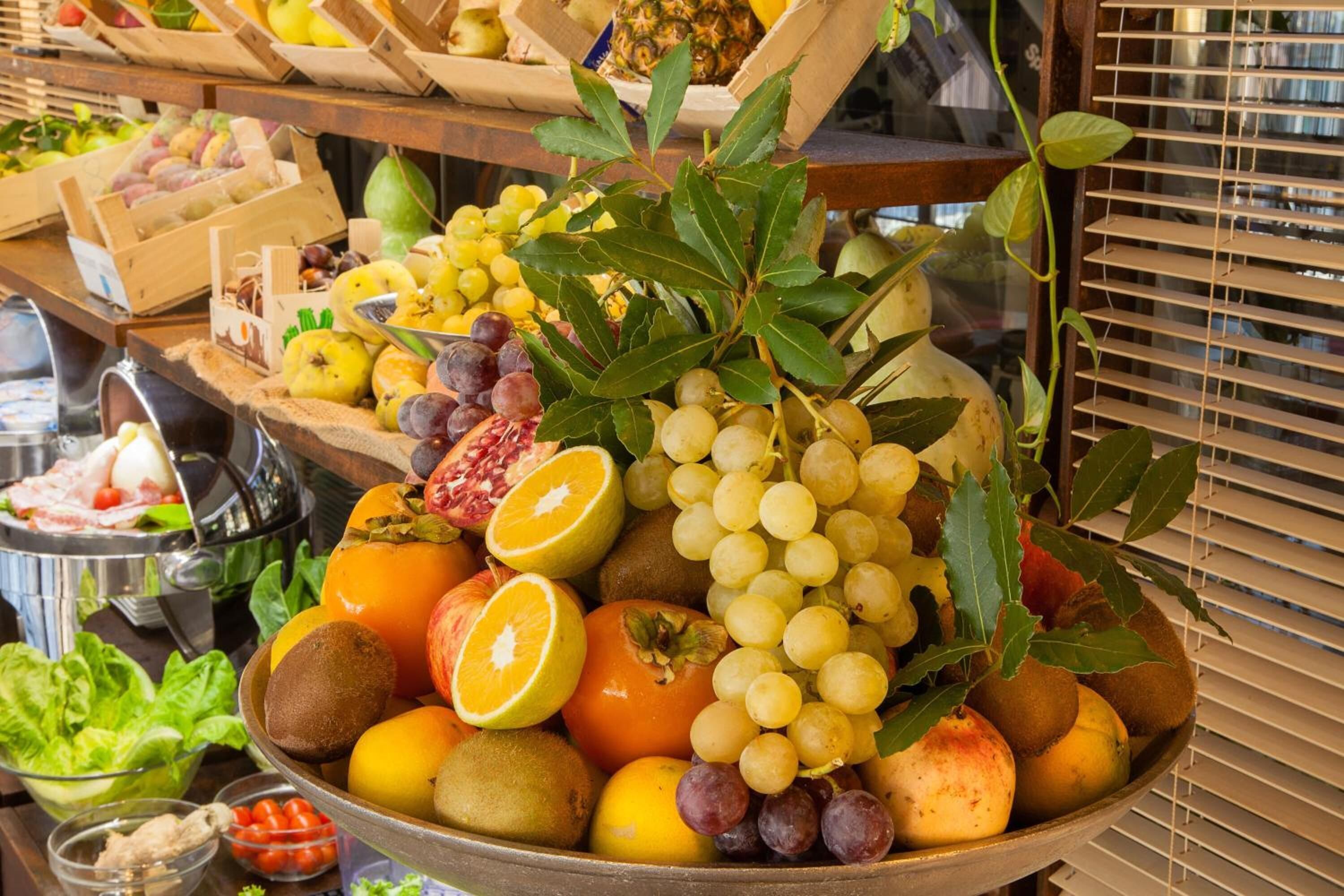 A fruit bowl with various fruits and a pomegranate on a table.