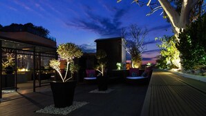 An outdoor patio area with seating and potted plants, under a night sky. - UNA Hotels One Siracusa Wellness & SPA (Syracuse)