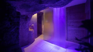 A hallway with a stone wall, a wooden door, and a purple-lit wall. - UNA Hotels One Siracusa Wellness & SPA (Syracuse)