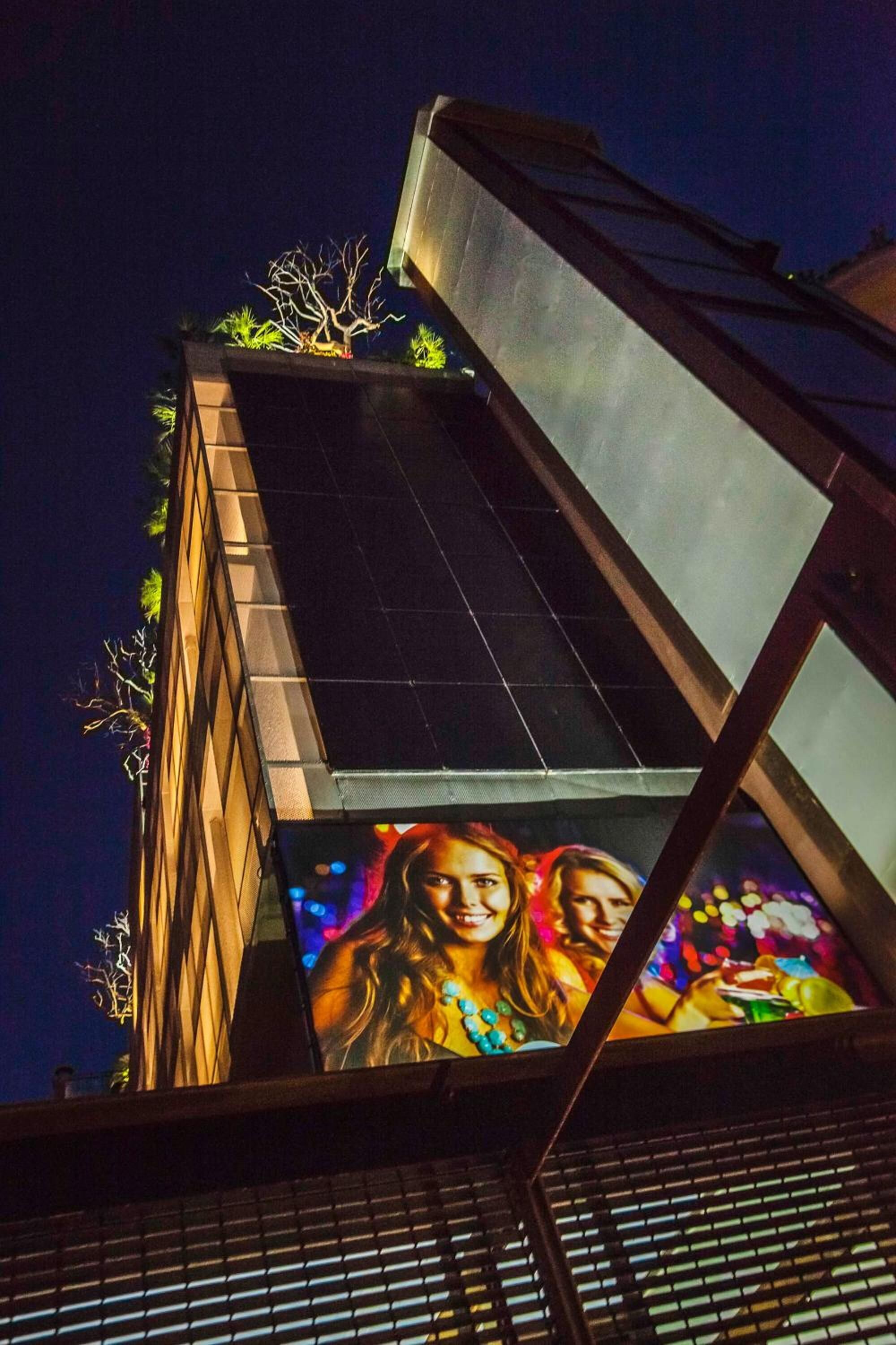 A building facade with a large illuminated mural of people.
