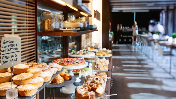 A bakery display with various baked goods and a sign indicating apple and jam cake. - UNA Hotels One Siracusa Wellness & SPA (Syracuse)