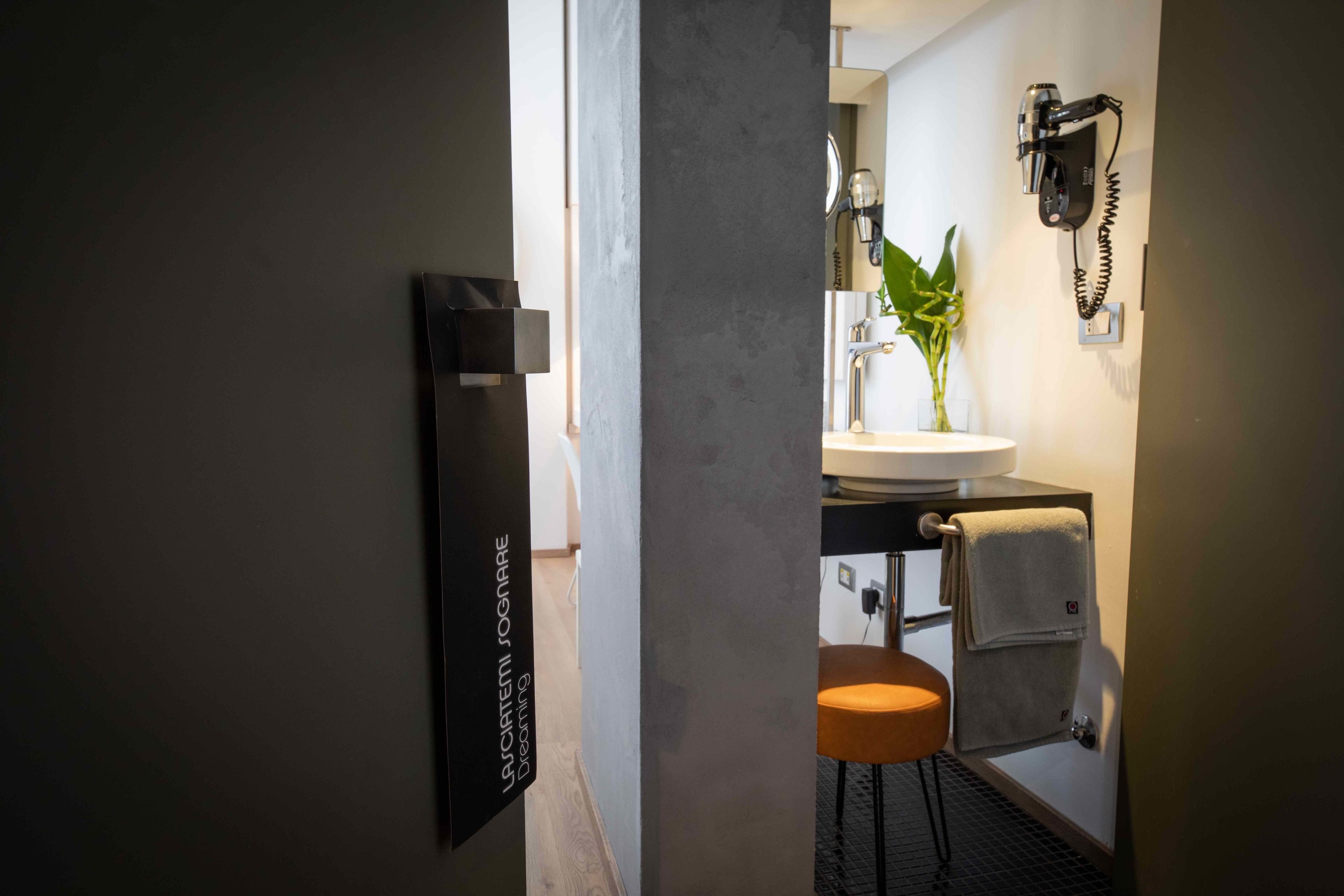 A modern bathroom with a sink, towel rack, and a hairdryer mounted on the wall.