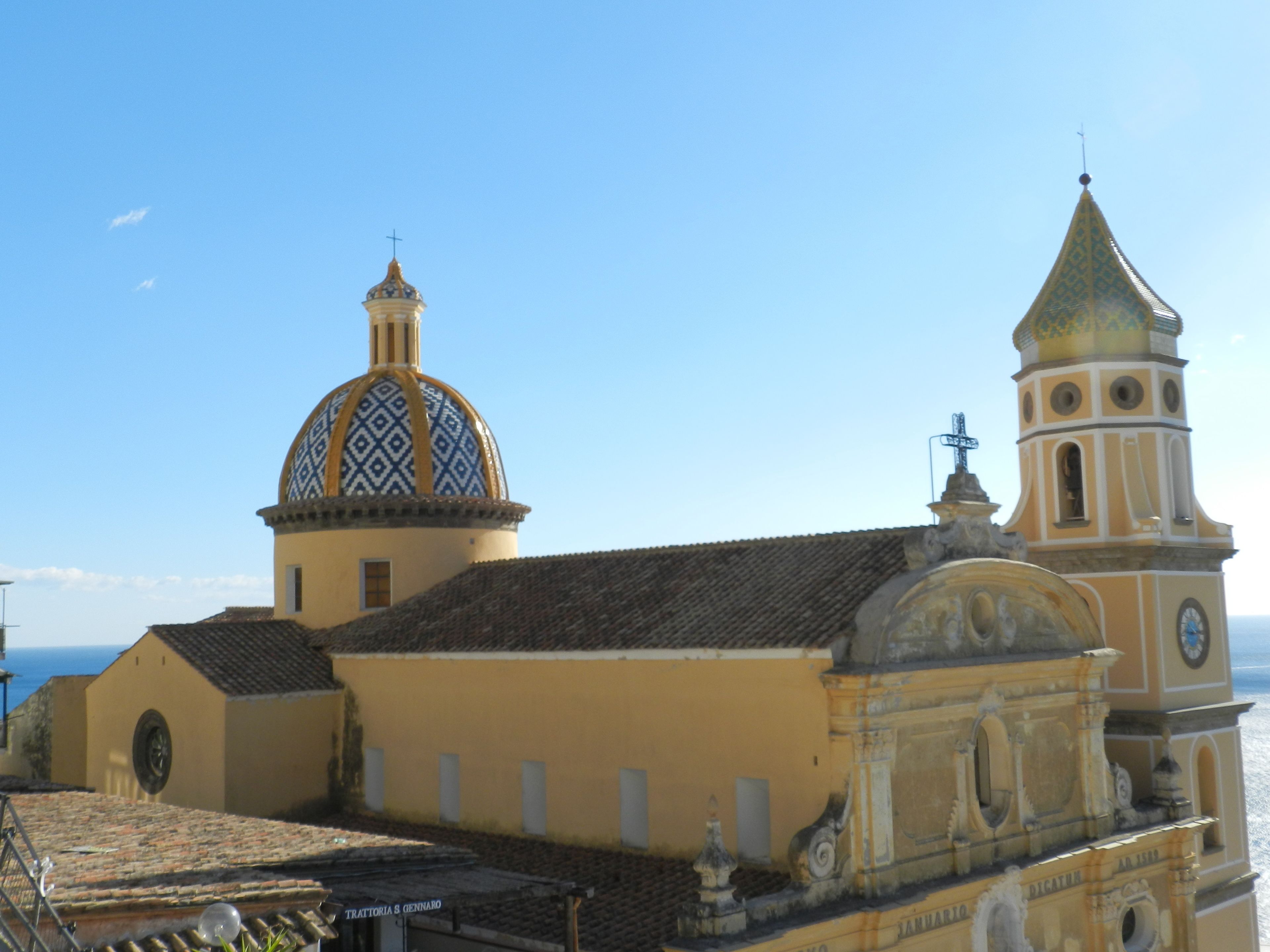 A church with a dome and bell tower, featuring a clock and a cross on top.