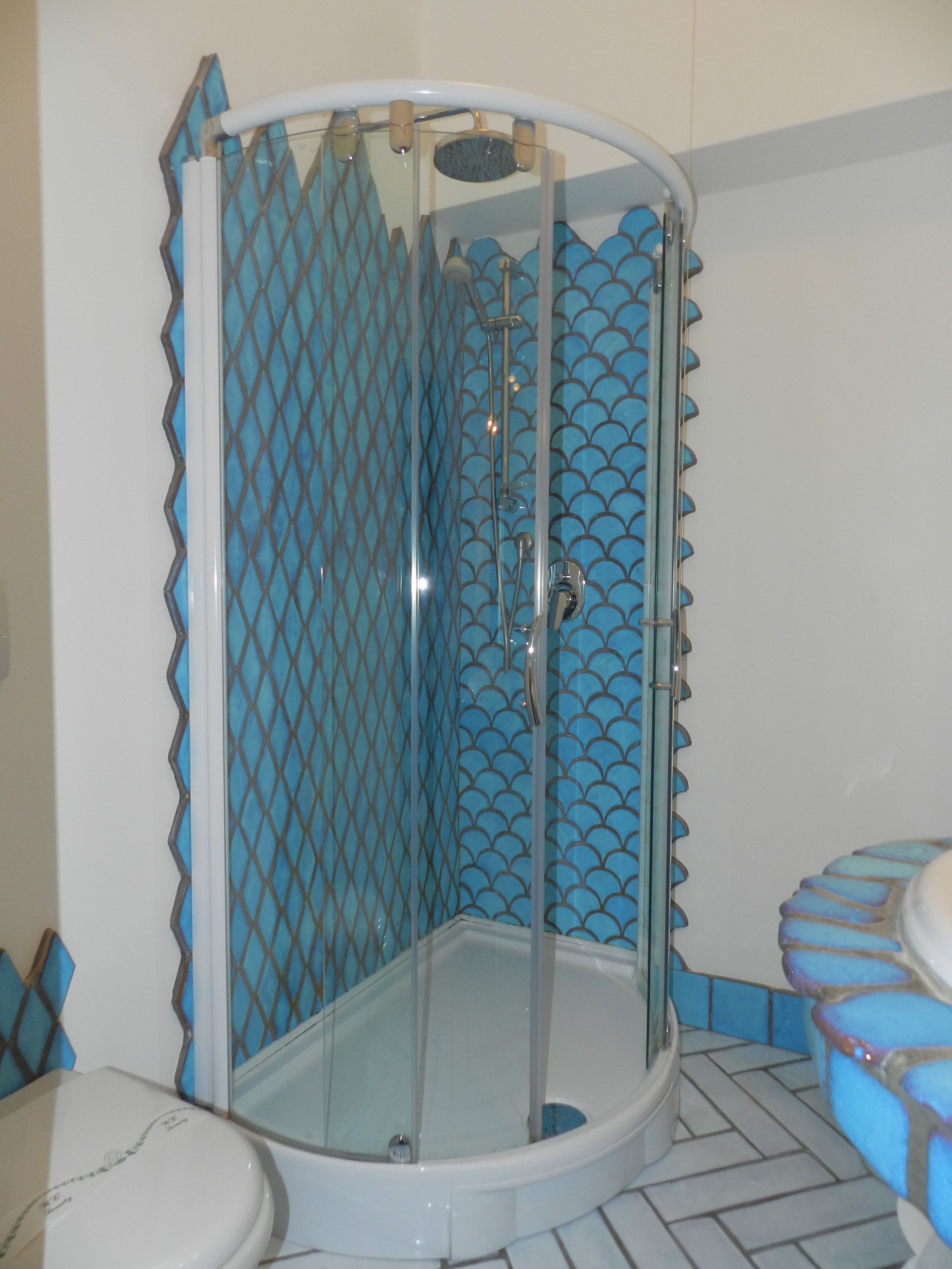 A shower enclosure with a glass door and a blue tiled interior.