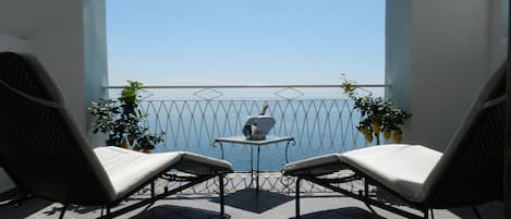 Un balcon avec deux fauteuils, une petite table et des plantes en pot.