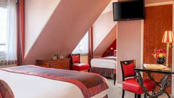 Une chambre d’hôtel avec un grand lit, un bureau avec une lampe, une télévision et une fenêtre avec des rideaux.