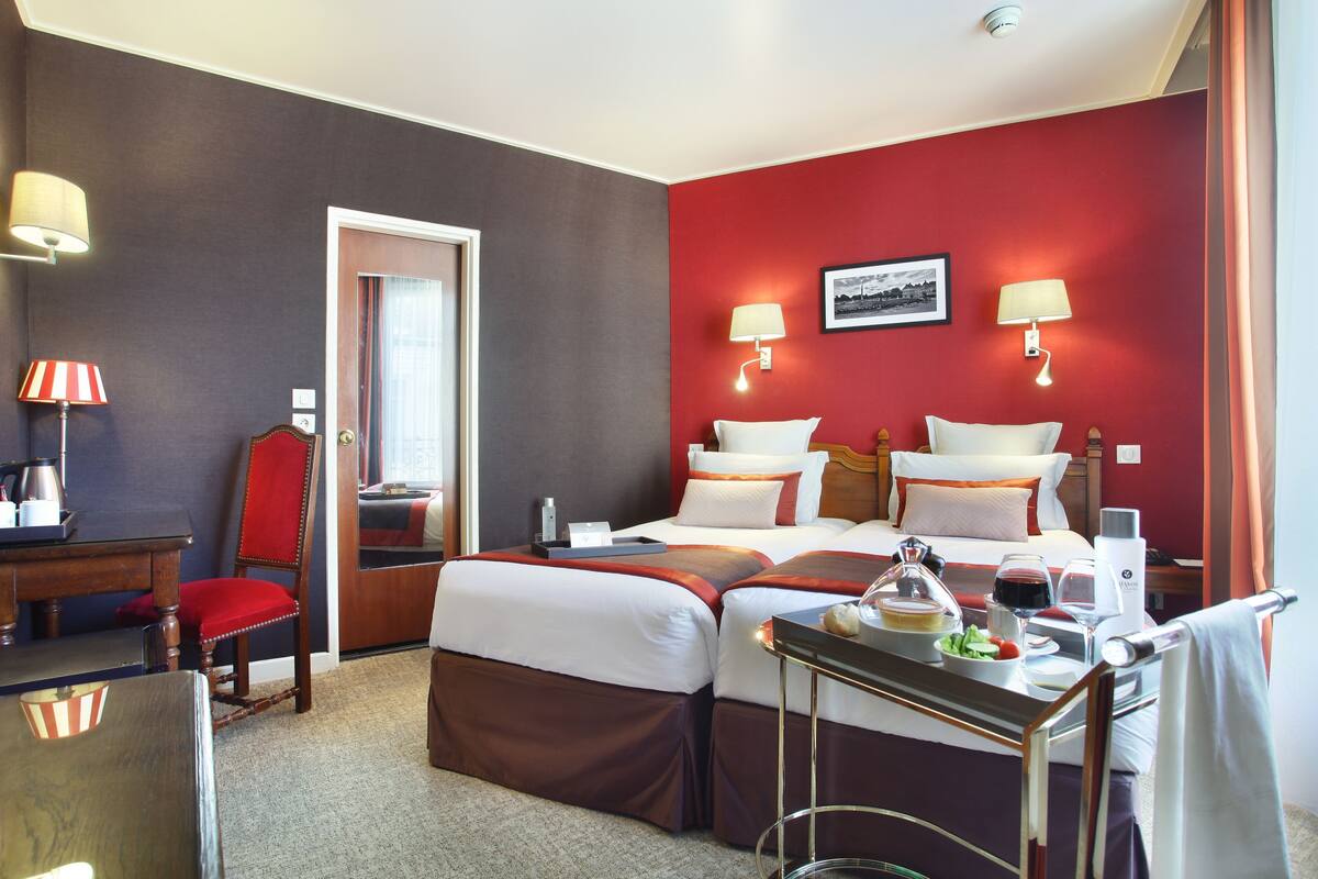 Ein Hotelzimmer mit Bett, Nachttischen, Schreibtisch, Stuhl und Esstisch mit Speisen und Getränken.