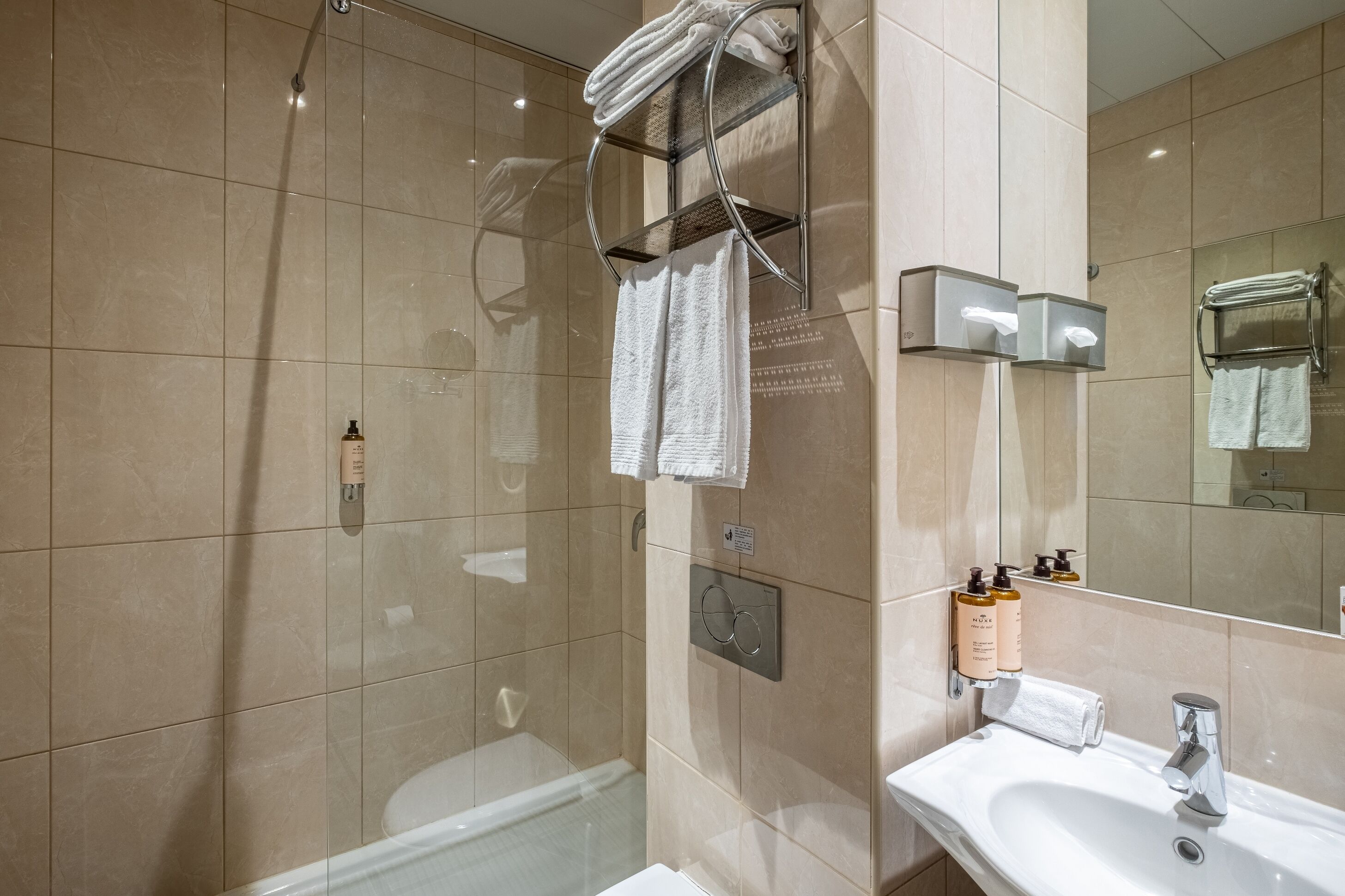A modern bathroom with a glass-enclosed shower, a white sink, and a mirror.