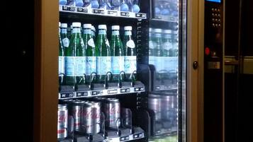 A vending machine stocked with various beverages including sodas, energy drinks, and snacks.