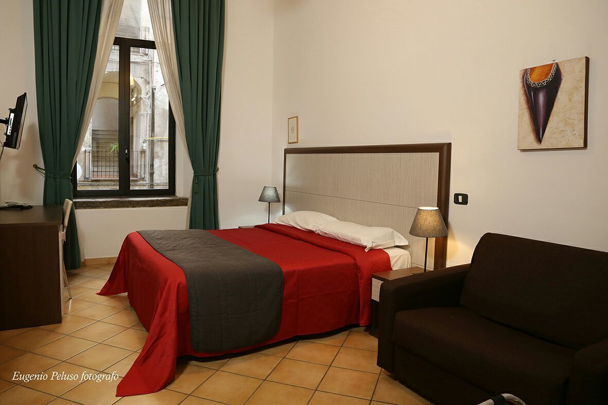 Una camera d'albergo con un letto, una scrivania, una sedia, una lampada e un quadro appeso al muro.