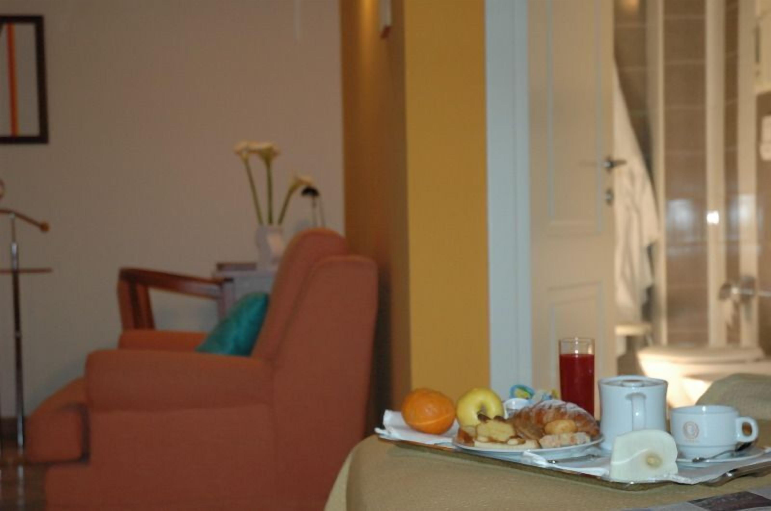 Un plateau de petit-déjeuner avec des croissants, des fruits et des boissons, posé sur une table dans une chambre d’hôtel.