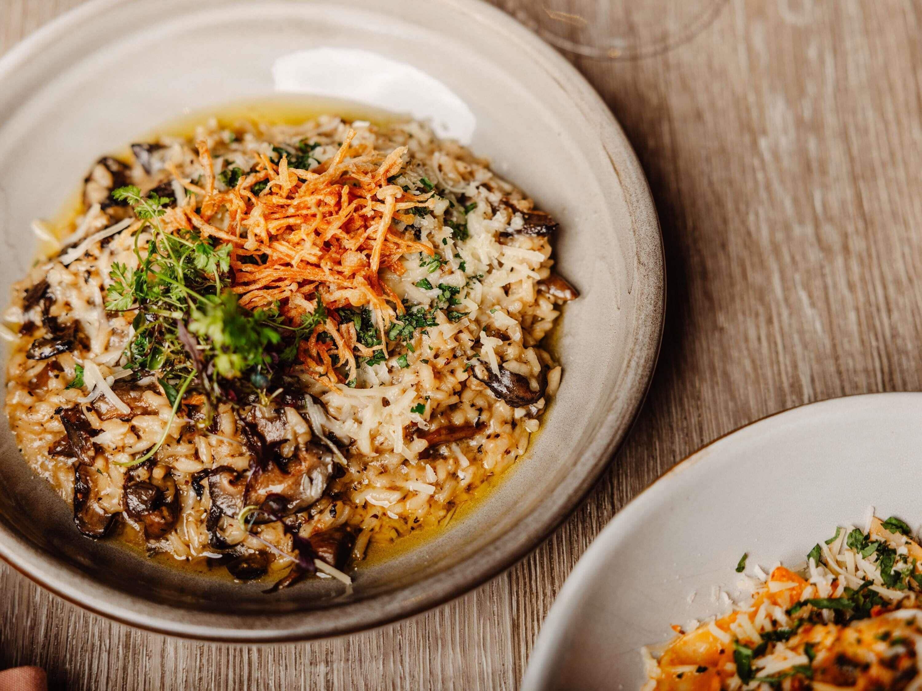 Uma tigela de comida com arroz, cogumelos e cenoura ralada.
