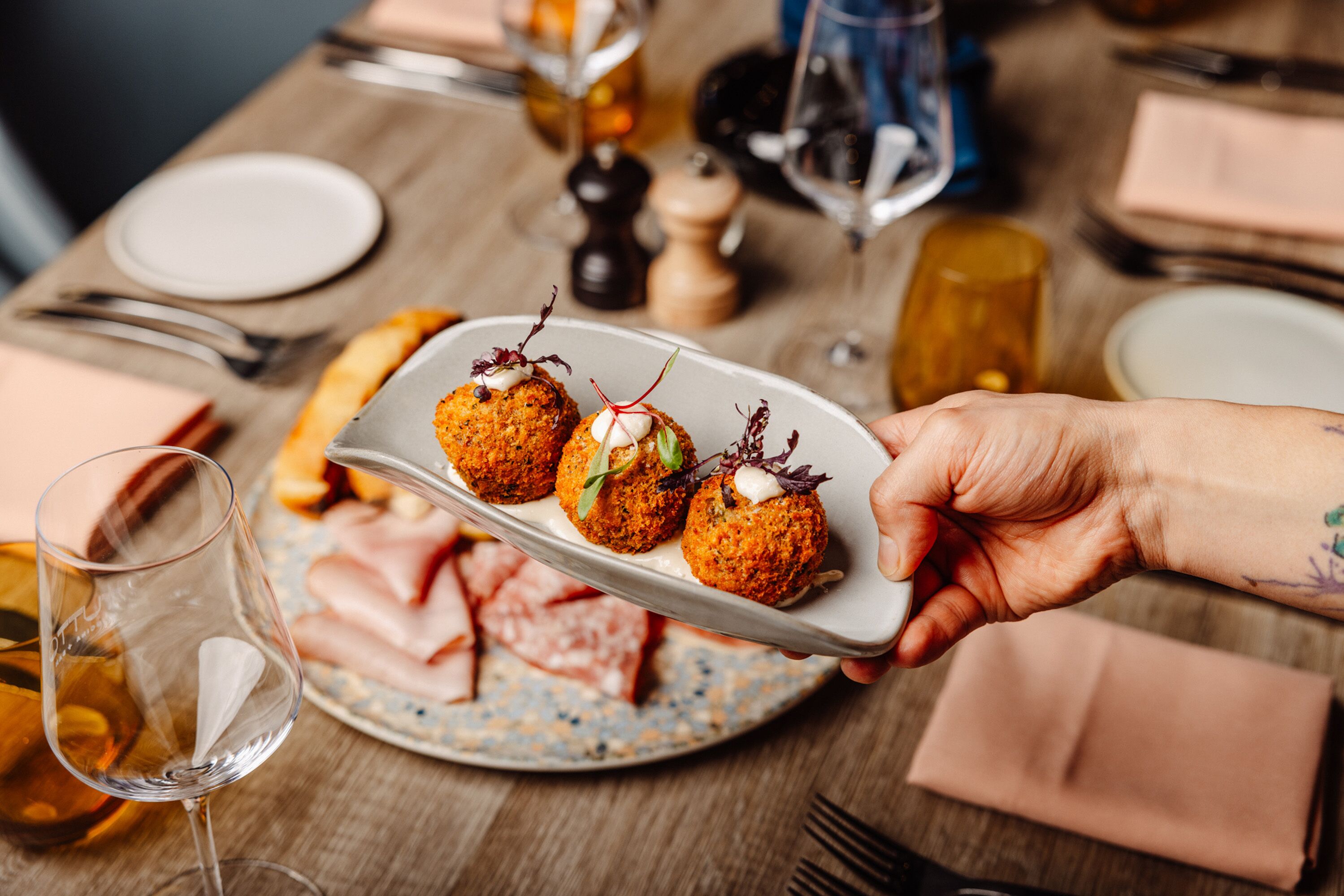 A dining table with plates of food, wine glasses, and cutlery.