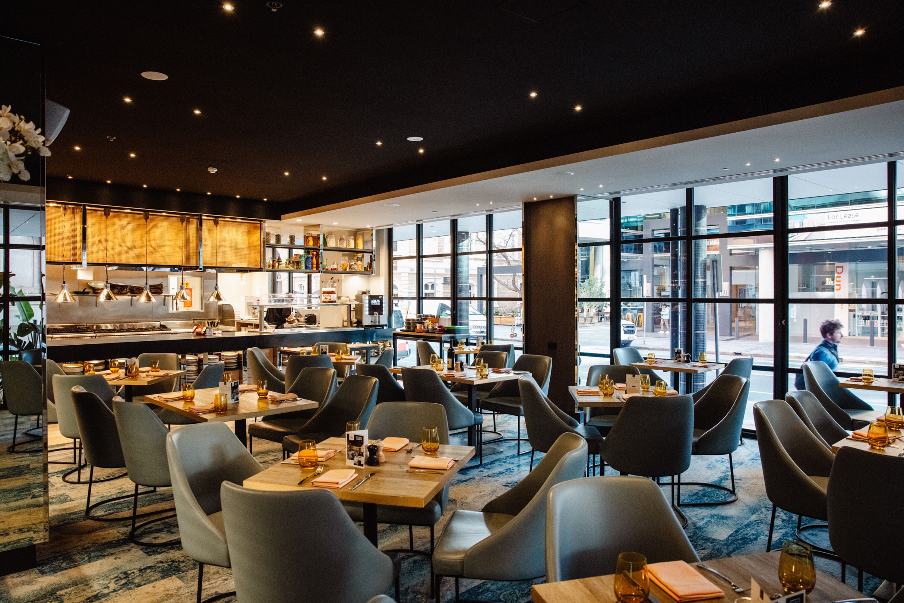 A modern restaurant with a central bar, multiple dining tables, and chairs.