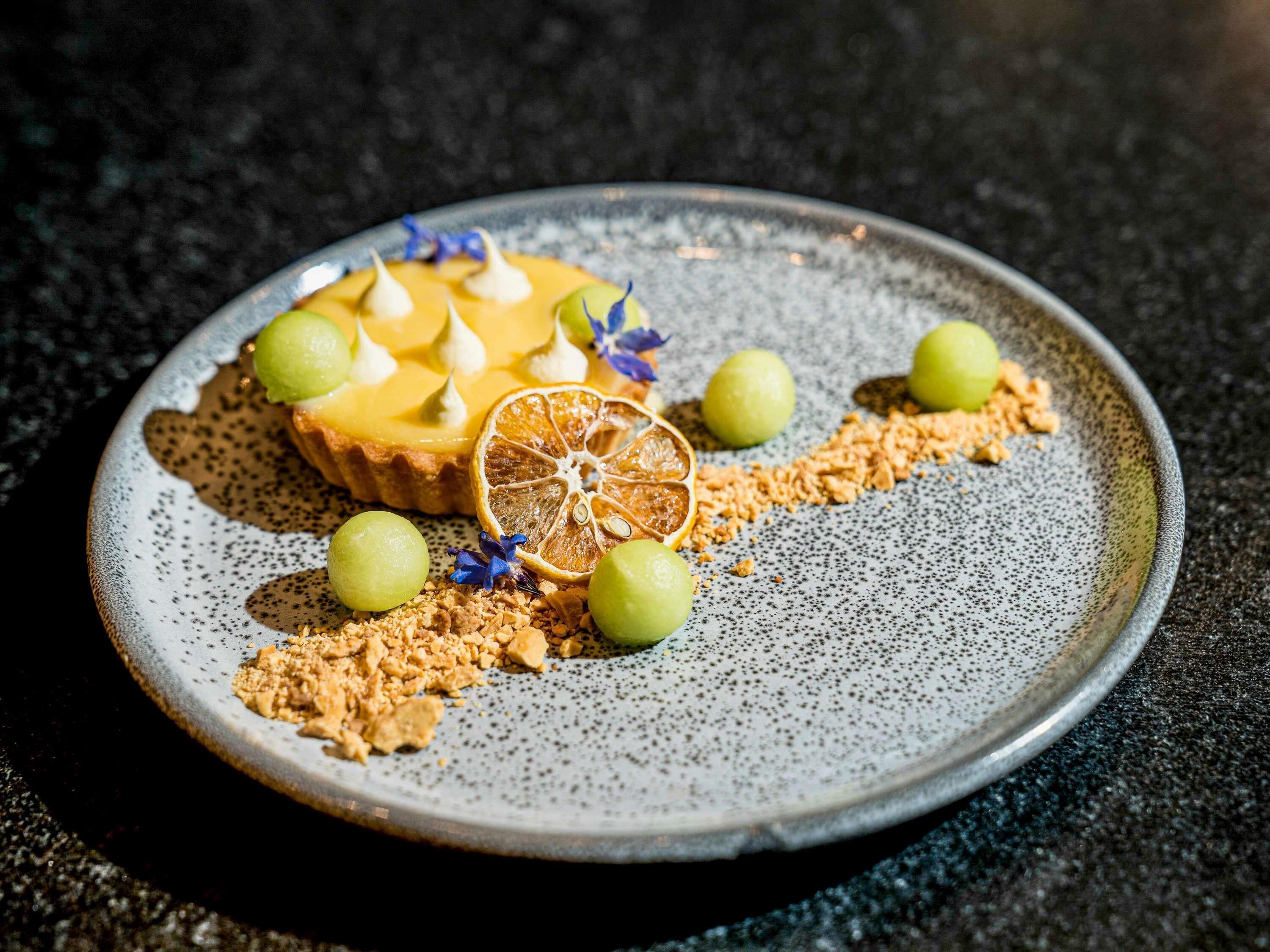 Un piatto dessert con una torta, meringa e guarnizione di frutta.